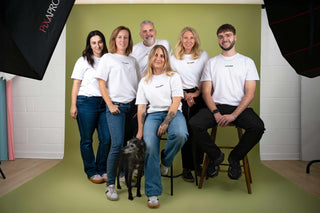 Group of people posing for a photo in a studio setting with green floor and white walls.
