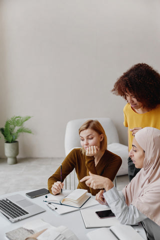 three women working together around a desk